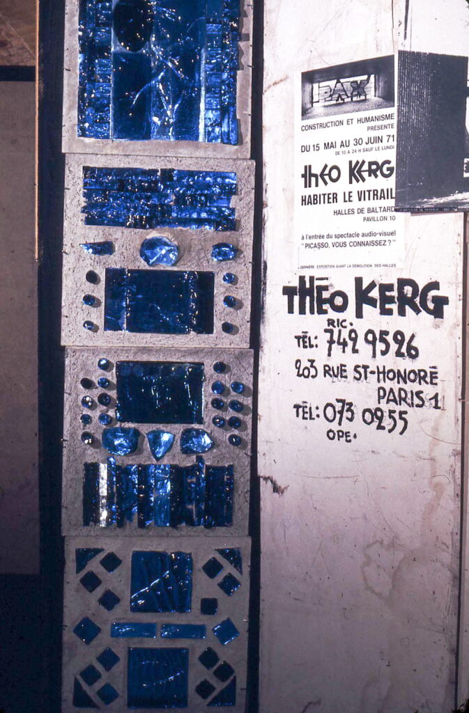 Panneau de vitrail en verre bleu conçu par Théo Kerg, exposé à côté d’une affiche annonçant l’exposition Habiter le vitrail aux Halles de Baltard à Paris en 1971.